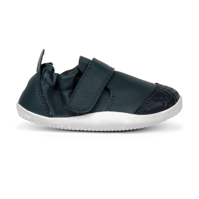 The Bobux Explorer Go First Walking Trainer Navy 501012B is a small, navy baby shoe with a white rubber sole, flexible design, hook-and-loop strap, elastic ankle for secure fit, and reinforced toe—perfect as first walking shoes., 9420062080245, 9420062080252, 9420062080269, 9420062080276, 9420062080283