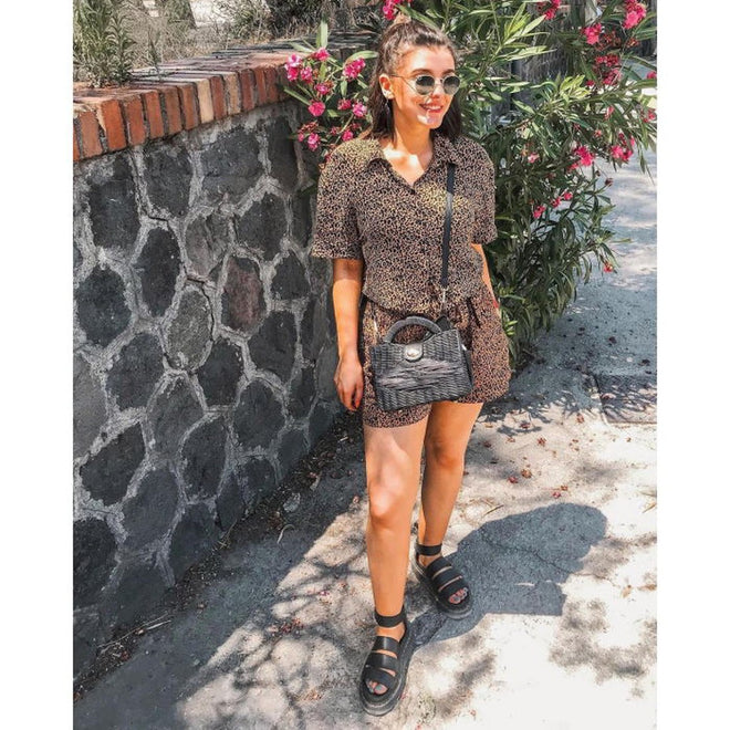 A model wearing a pair of Clarissa Quad sandals by Dr Martens in Black beside a stone wall, smiling and wearing shorts and a matching top.
190665248197,
190665248203,
190665248210,
190665248227,
190665248234,
190665248241,
190665248258,
190665248180,