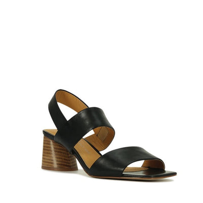 The EOS Peto Black Leather Sandal features an open toe, two wide straps, a closed heel with back strap, a medium stacked block wood-look heel, and a tan insole—perfect for businesswomen seeking minimalist style.