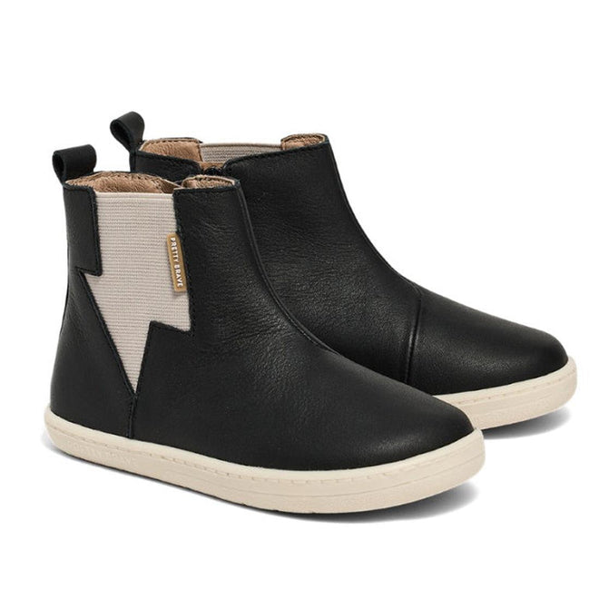 A pair of Pretty Brave Electric Leather Boot - Jet Black, ankle-high with white elastic side panels, cream rubber soles, and a subtle lightning bolt design, displayed on a white background.