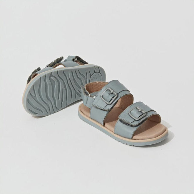 Pretty Brave Alex Leather Sandal Seaform Blue (sizes 29-33, CLEARANCE, NOT RETURNABLE) for kids features two adjustable buckle straps and textured rubber soles; one sandal is upright, the other shows the sole pattern., 9421036357684, 9421036357691, 9421036357707, 9421036357714, 9421036357721